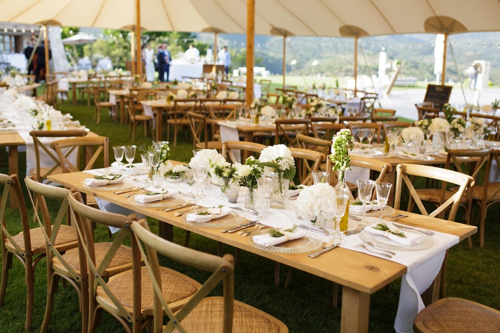 Свадьба в стиле рустик-шик: деревянные длинные столы с многоуровневыми цветочными композициями